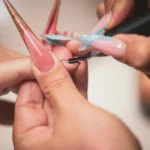A manicurist paints long artificial nails.