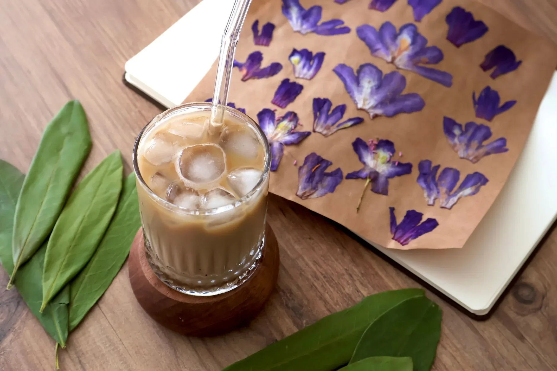 A refreshing iced coffee with floral decor on a wooden table.