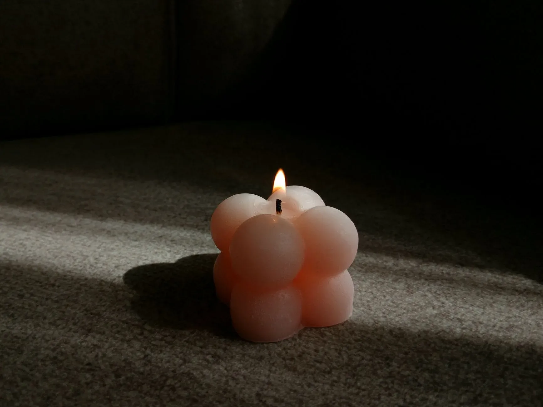 Elegant bubble candle casting a warm glow in a minimalist indoor setting.