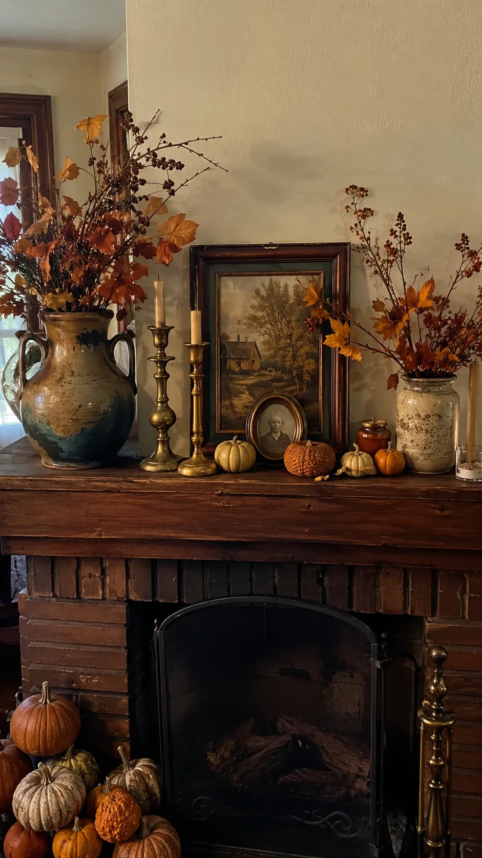 Vintage-style fall mantel with brass candlesticks, framed autumn artwork and ceramic pumpkins