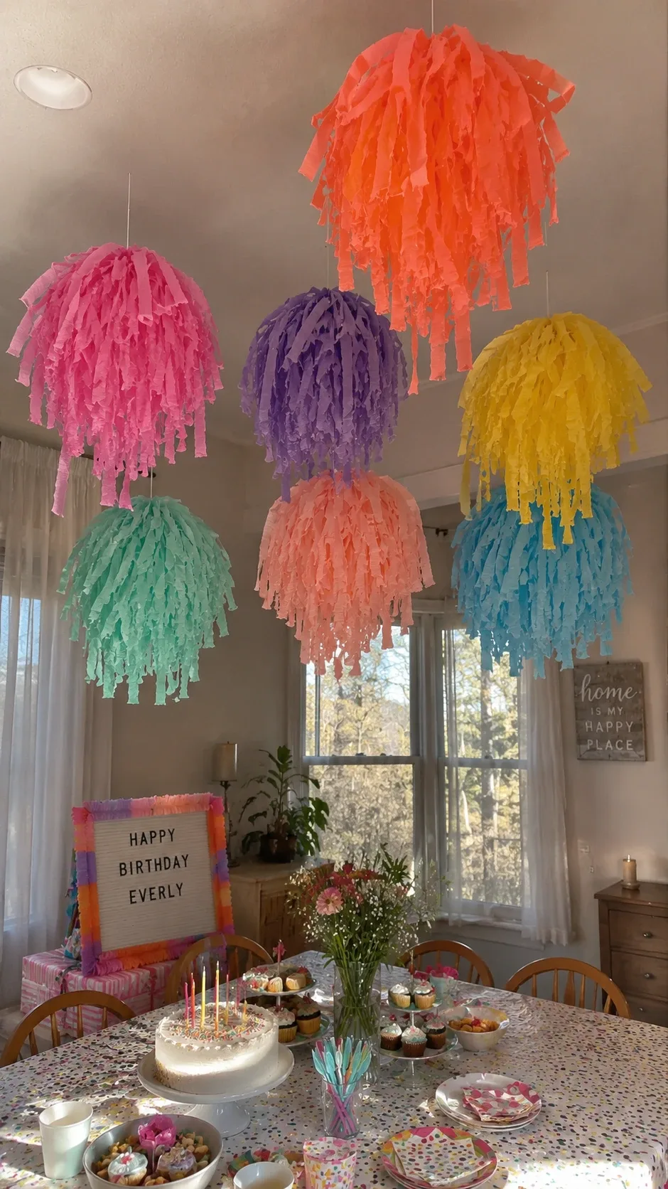 Hanging streamer tassel clouds in pastel colors over a birthday party table